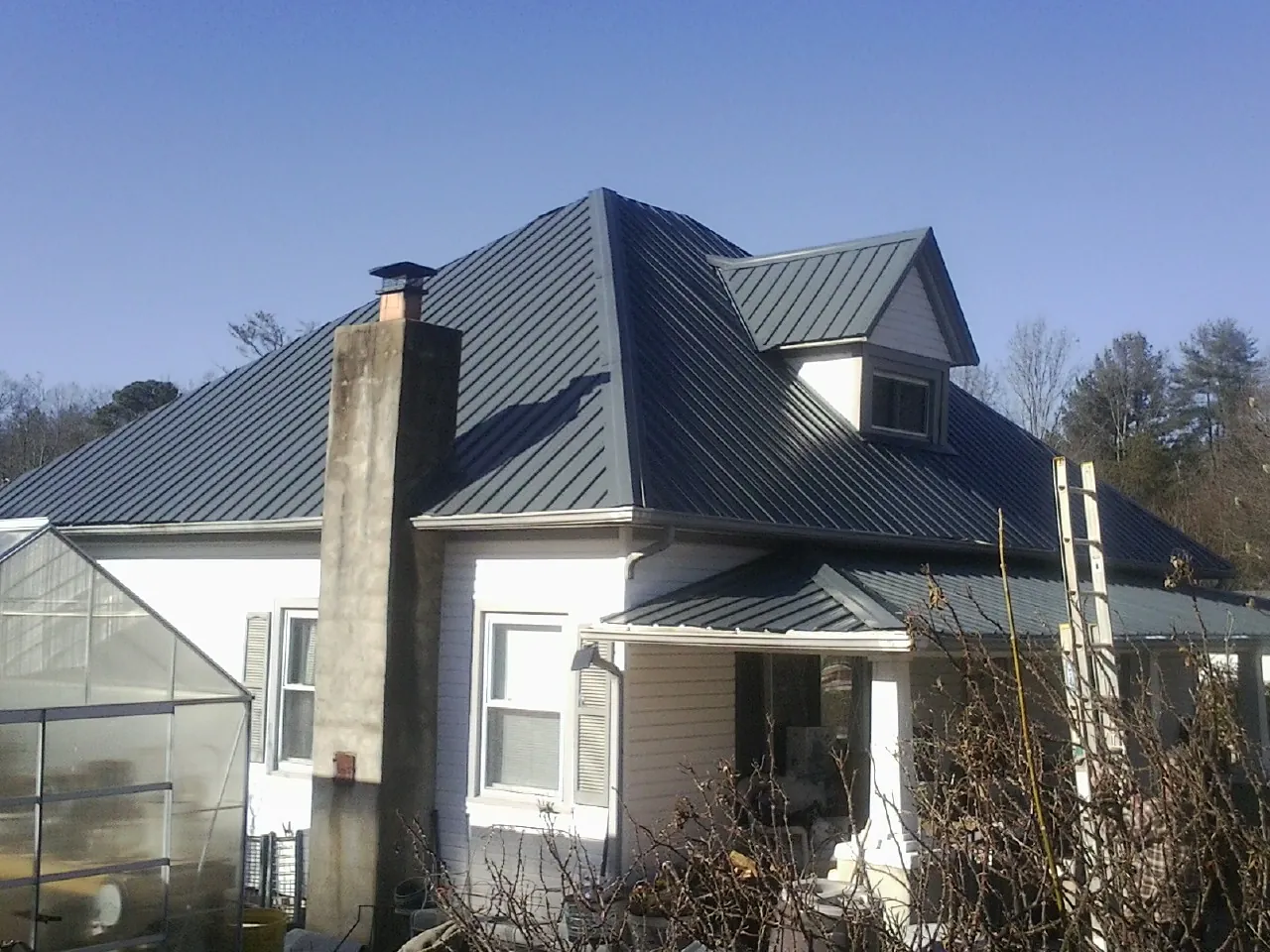 Dark blue standing seam metal roof on a white farmhouse with dormer — Slate & Tile Roof Repair by Roofing Brothers in River Forest