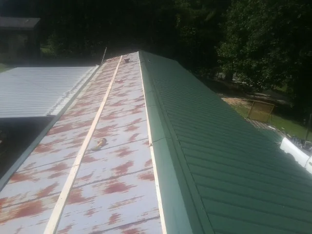 Old rusted panels beside newly installed green metal roofing — Wind Damage Roof Repair by Roofing Brothers in River Forest