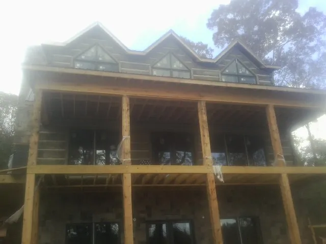 Dormers and porch framing on a large log home under construction — Roof Coating work by our crew in River Forest