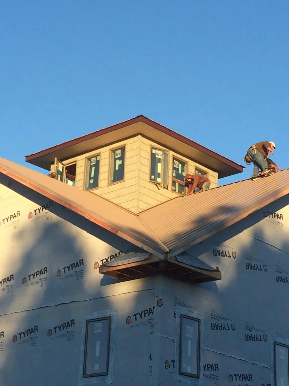Roofers working around a rooftop cupola on a new metal roof at sunset — Roof Waterproofing in River Forest by Roofing Brothers